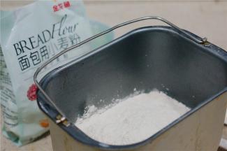 然后将金龙鱼面包用小麦粉称放至桶里面。再配入酵母及黑醋栗粉。