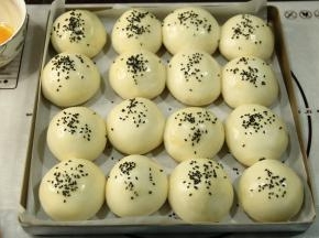 发酵完取出烤盘，预热烤箱上下185度。刷一层全蛋液，然后撒上黑芝麻。