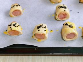 放在垫有油纸的烤盘上，刷上蛋液，撒上黑芝麻。