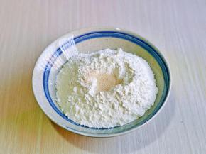 首先将面粉放入大口器具中，再面粉顶部挖了坑，加入酵母粉，分次加入温水，一边加水，一边用筷子搅拌。