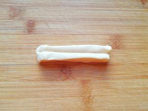 取一份条状面团，用刮刀从中间压一下，一个小油条生胚就做好了，依次做好剩下的小油条。