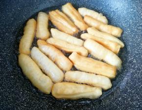 下入做好的油条生胚，炸至小油条飘起，颜色变至金黄色即可捞出。