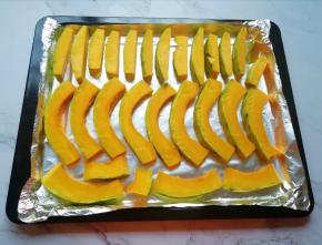 烤盘里铺上锡纸，将切好南瓜整齐的码在烤盘里。