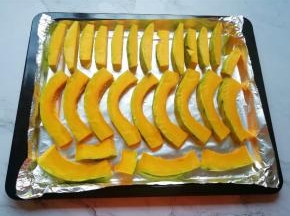烤盘里铺上锡纸，将切好南瓜整齐的码在烤盘里。