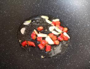 炒锅内倒适量的食用油烧热，下入蒜片和红辣椒炒出香味。