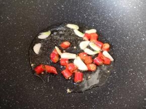 炒锅内倒适量的食用油烧热，下入蒜片和红辣椒炒出香味。