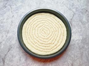 擀成一张和模具大小一致的面饼，放进披萨盘里，用叉子扎满小孔，防止饼皮在烤制的过程中中间凸起。