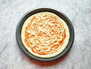 在饼底涂上番茄酱，撒上一层马苏里拉芝士。