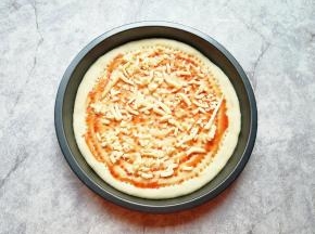 在饼底涂上番茄酱，撒上一层马苏里拉芝士。