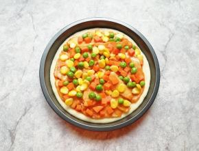 均匀的撒上焯熟的豌豆、玉米粒和胡萝卜。