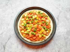 均匀的撒上焯熟的豌豆、玉米粒和胡萝卜。