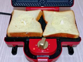 吐司片摆放在机器烤盘上，分别涂上奶油奶酪。