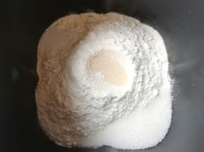 面包机桶内先打入一个鸡蛋，然后加入南瓜泥和水，再加入奶粉和高筋面粉，糖和盐对角放，面粉中间挖个小洞放入干酵母，用面粉盖上，选择“自动和面”10分钟。