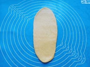 取一份面包面团擀成牛舌状。