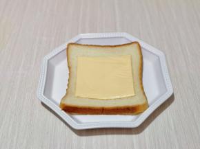 取一片吐司片，放入器具中，再放上一块奶酪片。