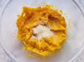 蒸熟的南瓜片从蒸锅里取出，放入盆里用勺子压成南瓜泥，晾至温热加入发酵粉搅拌均匀。