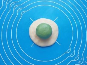 取一个油皮面团压扁，放上油酥面团包好。