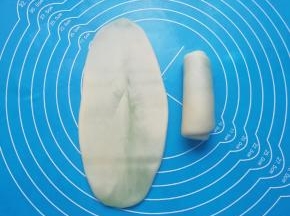包好的油酥皮擀开，然后卷起来，收口朝下摆放，盖上保鲜膜备用。