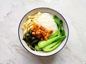 将泡好的米线放入碗里，依次放入青菜、豆腐皮、海带和炒好的豆腐干，根据自己的口味放盐和蔬之鲜。