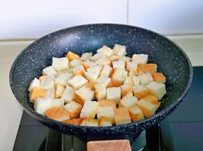 待黄油融化后，加入吐司丁，小火煎1分钟。