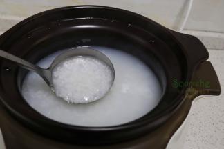 砂锅粥熬煮1个半小时之后，用勺子搅拌一下，可以看见米粒开花了，闻到一阵清新，把煎好的大闸蟹、生姜丝放入到粥里，合上盖子。