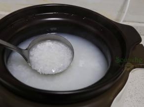 砂锅粥熬煮1个半小时之后，用勺子搅拌一下，可以看见米粒开花了，闻到一阵清新，把煎好的大闸蟹、生姜丝放入到粥里，合上盖子。