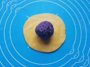 取一个小剂子压扁，用擀面杖擀成包子皮，放上豆沙馅。