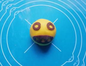 取一个包好的豆沙包，用剪刀在可可粉面片上剪出喜欢的图案，沾点水粘在豆沙包上面，一个搞怪的南瓜豆沙包就做好了，可以根据自己的喜好做出各种表情的豆沙包。