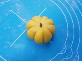 用刮板压出小南瓜的纹路，取一点点小面团加入可可粉揉匀，搓成条状做小南瓜的把，依次做好剩下的南瓜馒头。