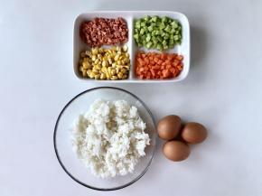 准备好福袋饭的食材，把胡萝卜和黄瓜洗净去皮，切碎，火腿肠切碎，玉米煮熟，剥粒。黄瓜皮削成长条，不要扔掉，还有用处。