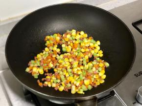 接着把火腿碎、黄瓜碎和玉米粒放入锅中翻炒。