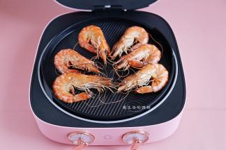 打开烤盘，将虾翻一下面，把孜然粉和辣椒盐撒上去。