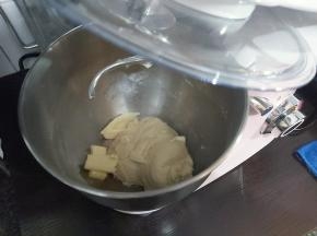 然后暂停机器，加入软化好的黄油跟玫瑰海盐，如果桶壁上有粉类残留，用刮板刮下来。（没有玫瑰海盐可使用一般的食盐）