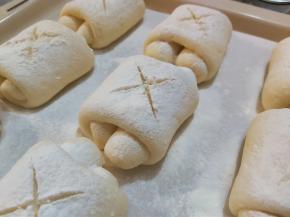 烤箱上下火180度预热至少十分钟，预热时，在小面包表面撒上一层高粉，表面用锋利的面包割刀划十字割口。（不喜表面上色太重，高粉可撒的稍微厚一点点）