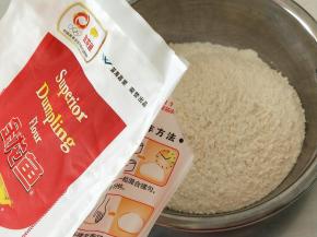 3.金龙鱼饺子专用麦芯粉200克倒入不锈钢盆里，加入盐和水搅拌成絮状