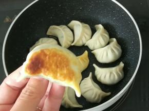 拿出不粘小奶锅，放少许花生油，然后码放好饺子，转小火慢慢煎到饺子底部金黄，如图。