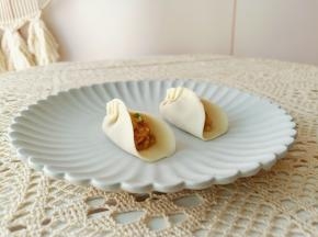 拿一张饺子皮放上肉馅包起来。