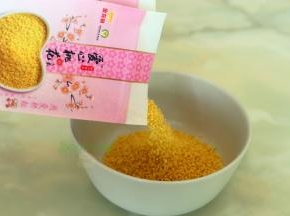 小米倒入碗里用清水清洗干净，挑选小米技巧，金龙鱼爱心桃花小米：外观粒大饱满，色泽金黄；口感味醇清香，熬粥米油 厚，米香浓郁，属于优质的小米。还具有安心养神，美容养颜的功效哦。