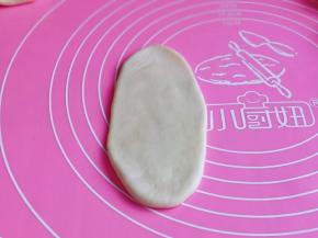 取一块面团，用擀面杖擀长舌状。