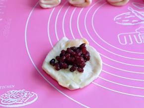 取一块面团，用掌心压出中间厚，周边薄的饼皮，再放上红豆馅，包起来，收口捏紧朝下，掌心轻轻按压一下。