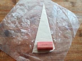 取一个热狗香肠，放在面片的底部，从下往上卷起来，几秒钟卷好一个，超快