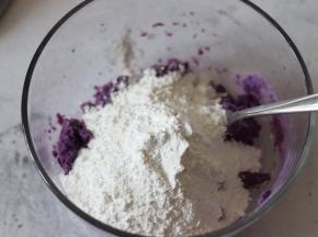 放入粘米粉和糯米粉的混合物，用叉子和紫薯泥混合，压拌的方法，慢慢的粉类和紫薯泥混合成有小块的散粒状。