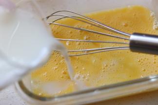 鸡蛋用打蛋器打散后，倒入温奶，边倒边搅拌，知道牛奶和蛋液混合均匀。