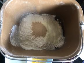 把除玉米油、蛋黄液、蓝莓果酱外的食材放入面包机桶内，启动揉面键揉成絮状