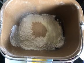 把除玉米油、蛋黄液、蓝莓果酱外的食材放入面包机桶内，启动揉面键揉成絮状