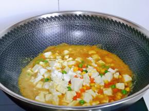 加入焯水的豆腐与时蔬，用铲子轻轻铲动，避免豆腐铲碎，淋上1小勺生抽，不要太多，再加入半小碗纯净水烧开。