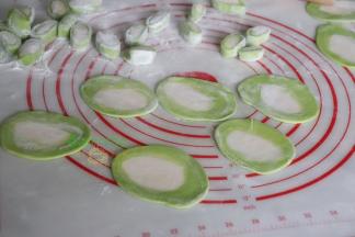 用擀面杖把小面团擀薄，饺子皮就做好了，中间是白色，外面是菠菜汁的绿色。