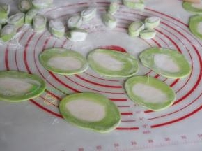 用擀面杖把小面团擀薄，饺子皮就做好了，中间是白色，外面是菠菜汁的绿色。