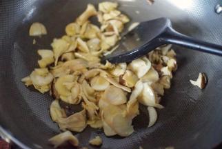 锅里热油后放入抽片的杏鲍菇煎炒至杏鲍菇成金黄色