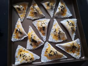 蛋黄加少许水，在榴莲酥表面抹蛋黄液，撒黑芝麻